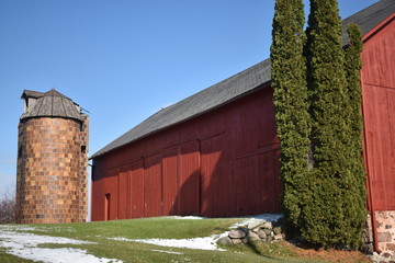 Fototapeta na wymiar Old red barn in early winter with just a touch of snow on a sunny day on a farm