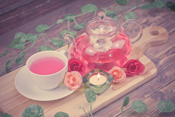 pot and cup of Rose tea on wood background