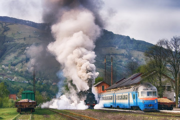 Fototapeta premium Steam train departure from the station in the mountains. Carpathian landscape, Rahiv, Ukraine. Active vintage transport.