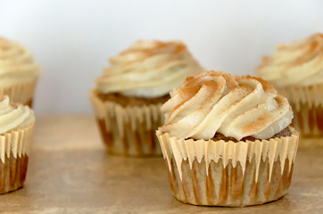 Chai-infused cupcakes with vanilla frosting on a wooden display tray