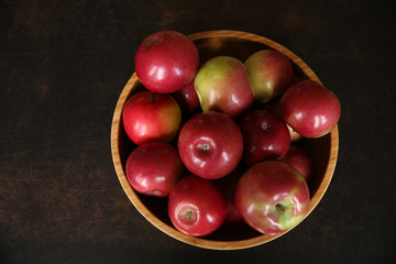red fresh apples in a wooden bowl on brawn wooden table. Healthy food. Flat lay. Top view.	
