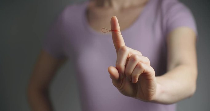 Woman showing a finger with a reminder knot on it.