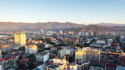 Batumi, Adjara, Georgia - October 2018: cityscape seen from the top of Sheraton sky bar during sunset golden hour with mountains in background