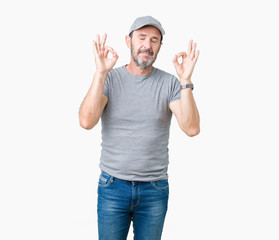 Naklejka premium Handsome middle age hoary senior man wearing sport cap over isolated background relax and smiling with eyes closed doing meditation gesture with fingers. Yoga concept.