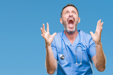 Middle age hoary senior doctor man wearing medical uniform over isolated background crazy and mad...