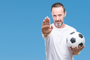 Middle age hoary senior man holding soccer football ball over isolated background with open hand doing stop sign with serious and confident expression, defense gesture