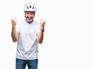 Middle age senior hoary cyclist man wearing bike safety helment isolated background celebrating surprised and amazed for success with arms raised and open eyes. Winner concept.