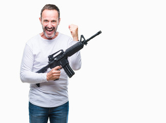 Middle age senior hoary criminal man holding gun weapon over isolated background screaming proud and celebrating victory and success very excited, cheering emotion