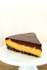 A slice of vegan cheesecake covered in chocolate