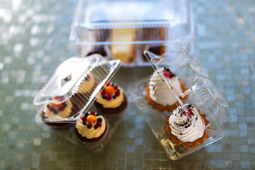 Cakes in a plastic disposable container on a colored background