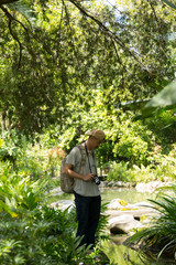 Photographer take photo in the garden. A man standing on stone.