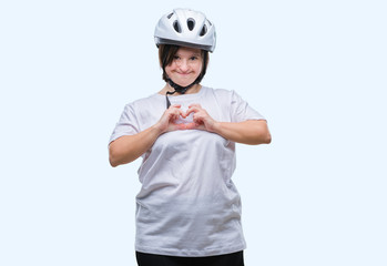 Young adult cyclist woman with down syndrome wearing safety helmet over isolated background smiling in love showing heart symbol and shape with hands. Romantic concept.