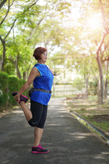Senior asian woman stretch muscles at park and listening to music. Athletic senior exercising together outdoor. Fit senior runners stretching before running outdoors