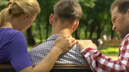 Parents supporting upset son after failed examination, family support and care