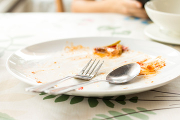 Closeup of Empty white dish with fork and spoon after eating on the table