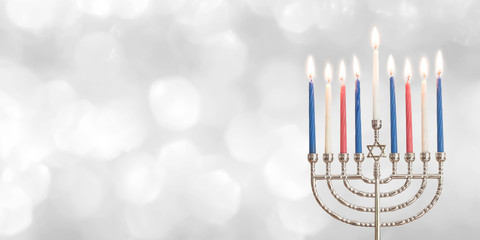 Hanukkah Chanukah Jewish holiday background with menorah (Judaism candelabra) for Festival of Lights and Feast of Dedication with burning candles and traditional on white silver winter snow bokeh