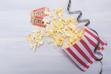 package with scattered popcorn, two movie tickets and film, on a light gray background