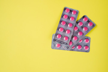 A lot of pink medicine pills.Medicine pills blister packs pile, isolated on yellow background.Pharmacy theme, Heap of pink round medicine tablet antibiotic pills.Copy space
