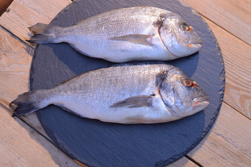 dorado fish on a black plate and wooden table