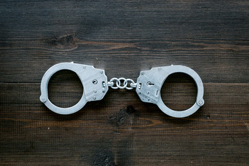 Metal handcuffs on dark wooden background top view copy space