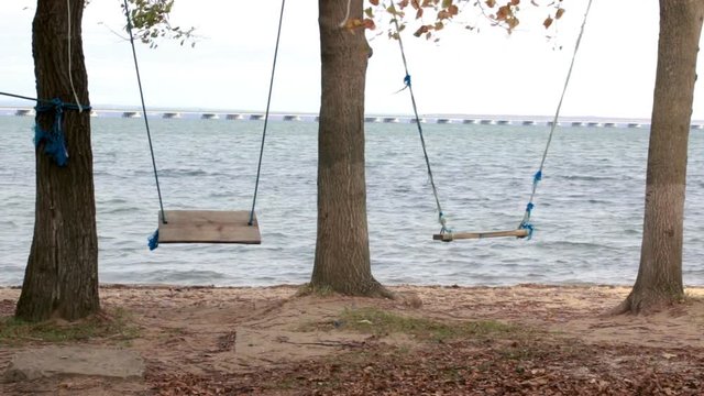 Swing in a recreation park and a view from the shore to a low-water bridge from the Sedanka station to the De Friz peninsula through the Amur Bay in the far east city of Vladivostok.