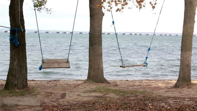 Swing in a recreation park and a view from the shore to a low-water bridge from the Sedanka station to the De Friz peninsula through the Amur Bay in the far east city of Vladivostok.