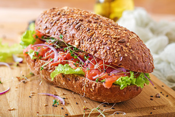 Salmon sandwich - smorrebrod with cheese cream and microgreen on wooden table.