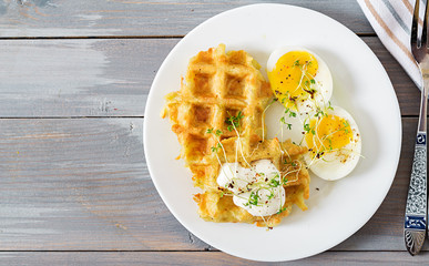Healthy breakfast or snack. Potato waffles and boiled egg on grey wooden table. Top view. Flat lay