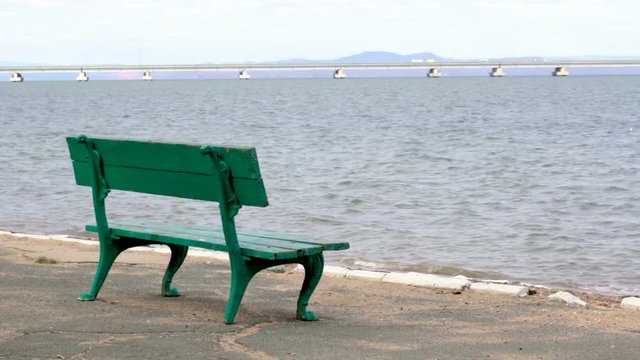 A rest park bench and a view from the shore of a low-water bridge from the Sedanka station to the De Friz peninsula across the Amur Bay in the far east city of Vladivostok.
