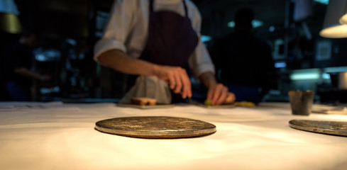 Metal plate on a white table cloth with the chef in the background.