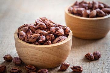 Roasted striped peanuts in wooden bowl