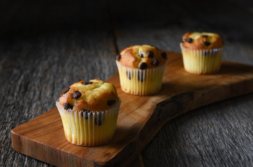 Closeup of three mini chocolate chip muffins on a cutting board