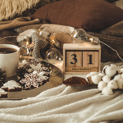 Old vintage wooden calendar set on the 31 of December with cup with tea or coffee, cookies in the...