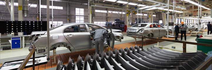 Engineer looks into the cab of the car on the production line. Automotive production line. long format. Wide frame