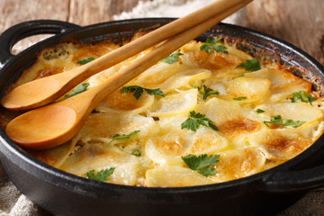 Finnish Janssonin Kiusaus hot baked potatoes with anchovies, onions and heavy cream close-up in a frying pan. horizontal