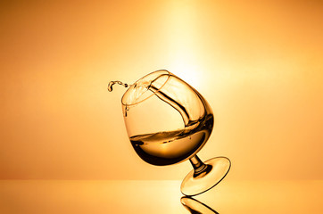 vine spills out of the glass. splash of cognac in glass