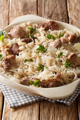 Delicious traditional Estonian mulgikapsas  stewed pork with sauerkraut and barley close-up in a pan. vertical