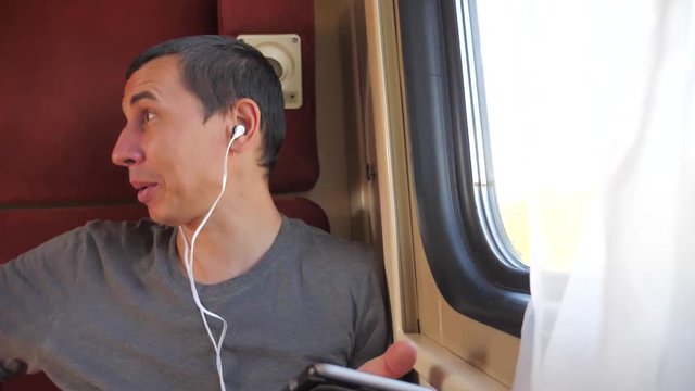 man listening to the music on the train lifestyle rail car coupe compartment travel. slow motion video. man with a smartphone at the window of a train in a car travel internet social media web. man