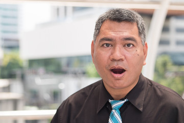 surprised old business man. portrait of excited businessman looking at you with surprise, open mouth or jaw dropping pose. southeast asian middle aged man model.