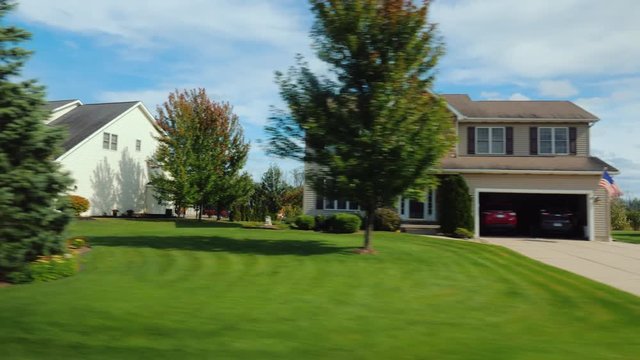 Drive along an area with typical US homes surrounded by green lawns.