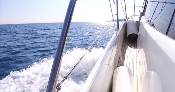 On board side view of a yacht navigating on blue sea vawes. Luxury yacht floats on blue sea waves.  Sailing in the wind through the waves 