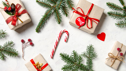 Christmas background with homemade wrapped in craft paper christmas presents, candy cane and fir branches on wooden surface. Top view