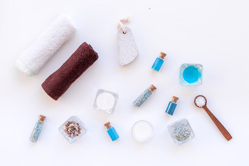 Sea salt for spa and aroma spa cosmetics near towel and shells on white background top view