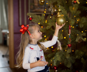 girl decorates Christmas tree at home