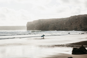 Surfer walks into the water to surf. Active and extreme sport. Surfing. Interesting hobby or...