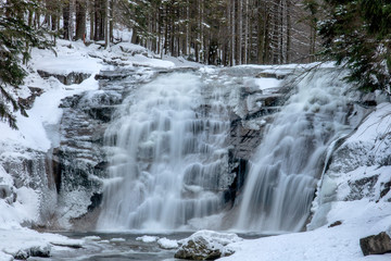 Waterfall in snowy forest. Winter Mumlava Waterfall in Harrachov, Krkonose mountains, Czech Republic