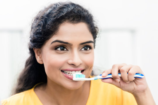 Close up portrait of a beautiful young woman brushing teeth in the morning
