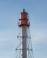 Metal lighthouse on blue sky background.