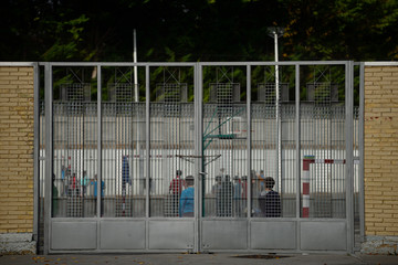niños en el recreo detrás de la puerta de rejas de un colegio