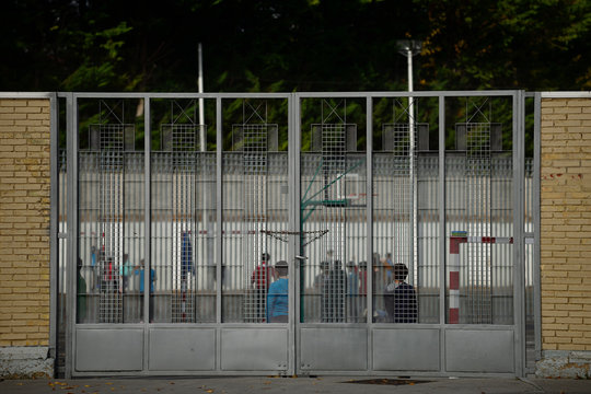 ni&ntilde;os en el recreo detr&aacute;s de la puerta de rejas de un colegio